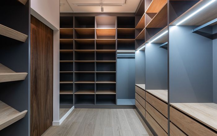 Einbauschrank mit vielen offenen Fächern und geschlossenen Auszügen in einem Ankleideraum.